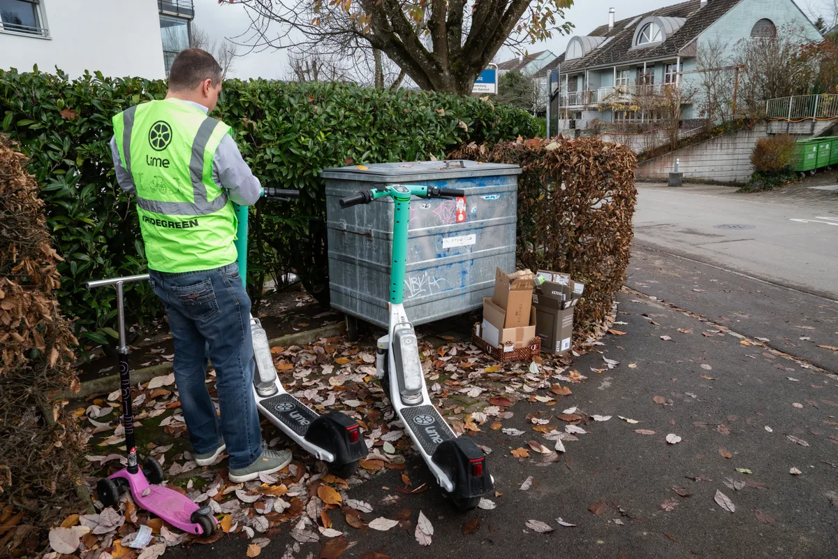 Mann mit gelber Weste steht vor zwei Lime-Fahrzeugen.